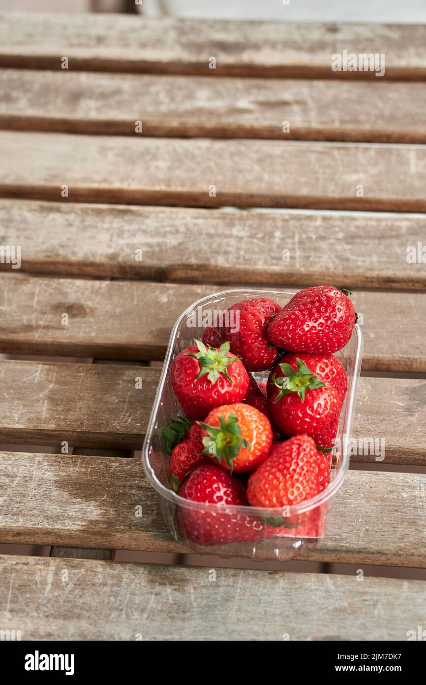 A vertical top view of red luscious strawberries in a small transparent ...