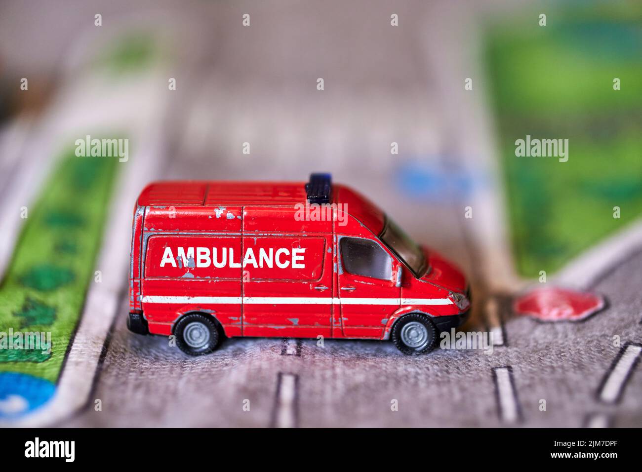 A closeup of a Siku brand red toy model ambulance van on the play road Stock Photo