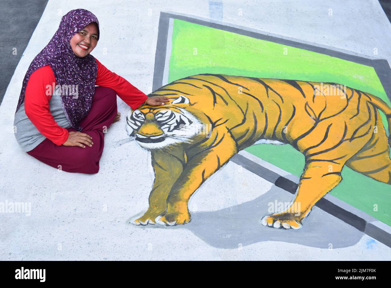 A resident poses with a 3D (3D) tiger painting in Bojonggede, Bogor  Regency, Indonesia, Friday (7/8/2020 Stock Photo - Alamy