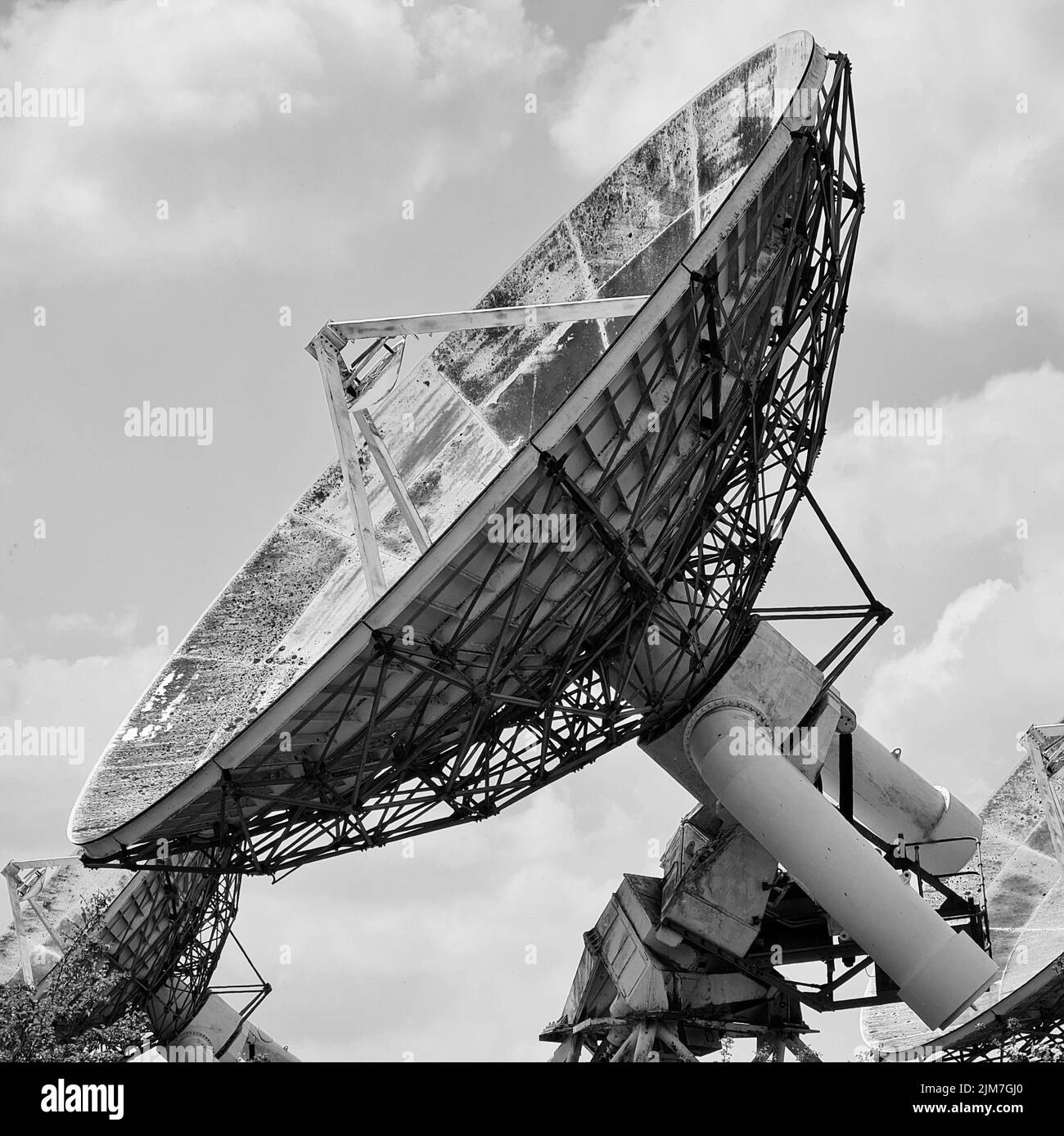 A radio astronomy observatory telescope covered in dirt points at 45 degrees into the sky. Stock Photo