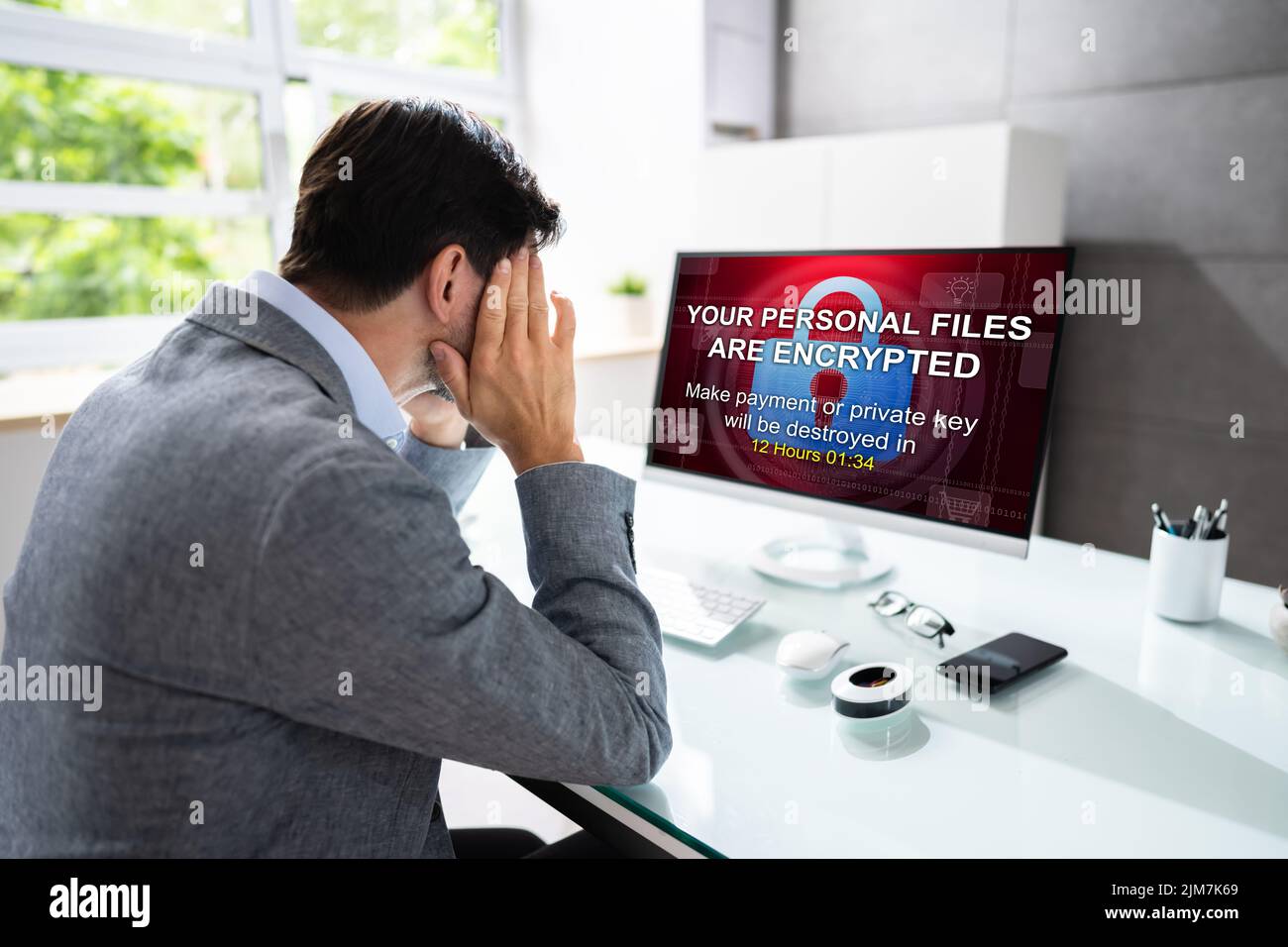 Worried Businessman Looking At Computer With Ransomware Word On The Screen At The Workplace Stock Photo
