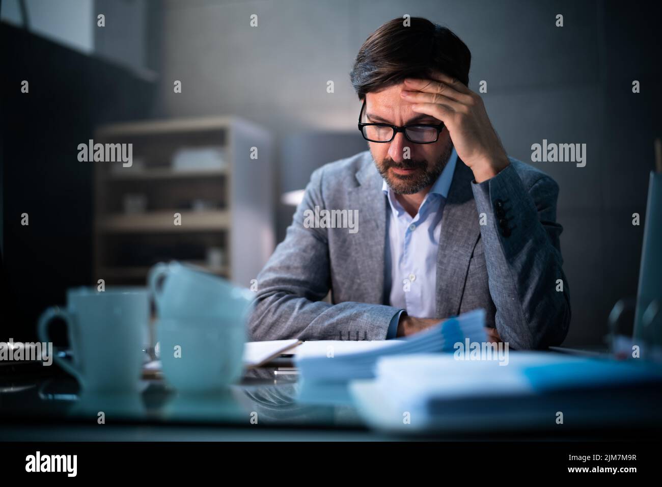 Workplace Headache Pain And Stress. Business Man In Dark Alone Stock Photo
