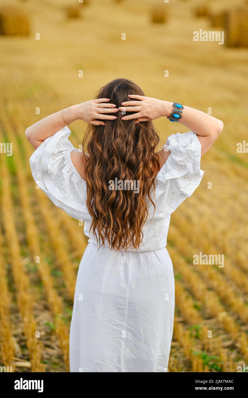 Rear view of pretty young woman holding hands behind her head while ...