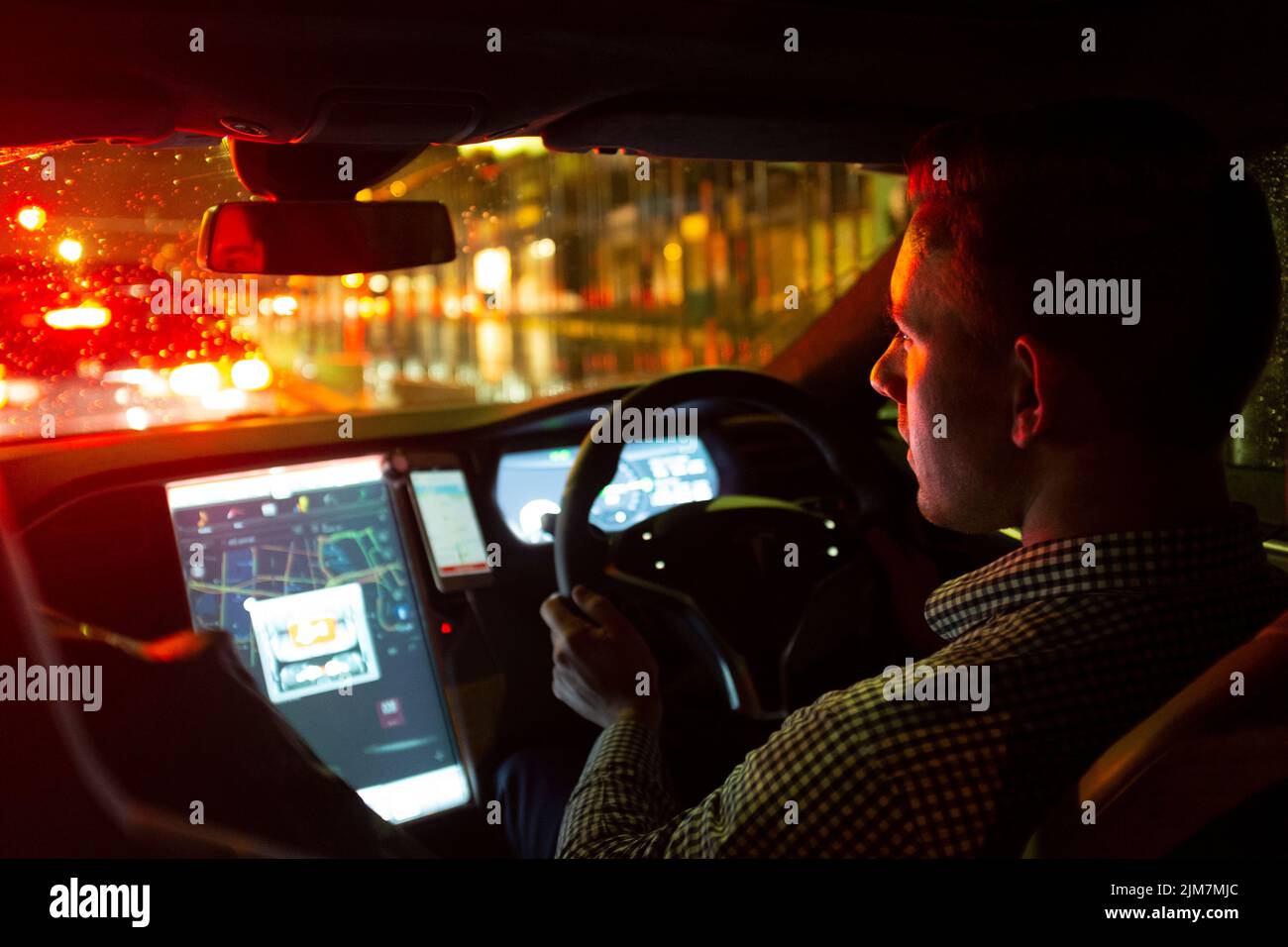 Uber driver driving a Tesla car on a rainy night in Sydney, Australia Stock Photo