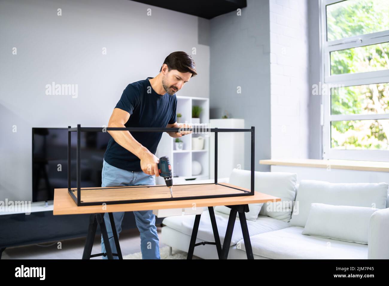DIY Table Assembly In Domestic Apartment. Concentrated Carpenter Stock Photo