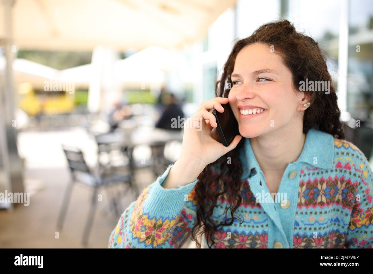 Happy woman talking on phone sitting in a coffee shop Stock Photo