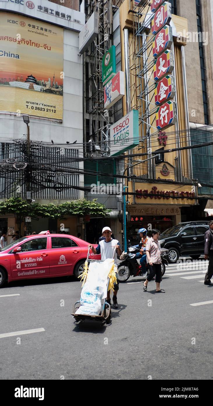 Delivery man pushing a hand truck Yaowarat Road in Samphanthawong District Chinatown Bangkok Thailand Stock Photo