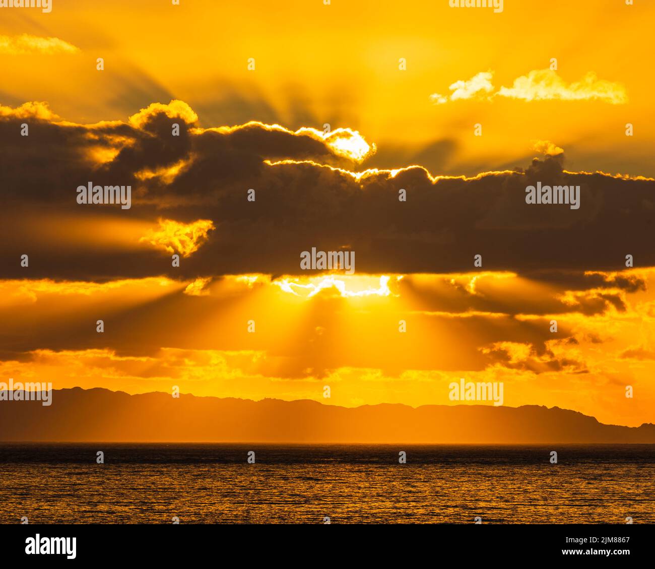 Sun behind clouds over sea Stock Photo
