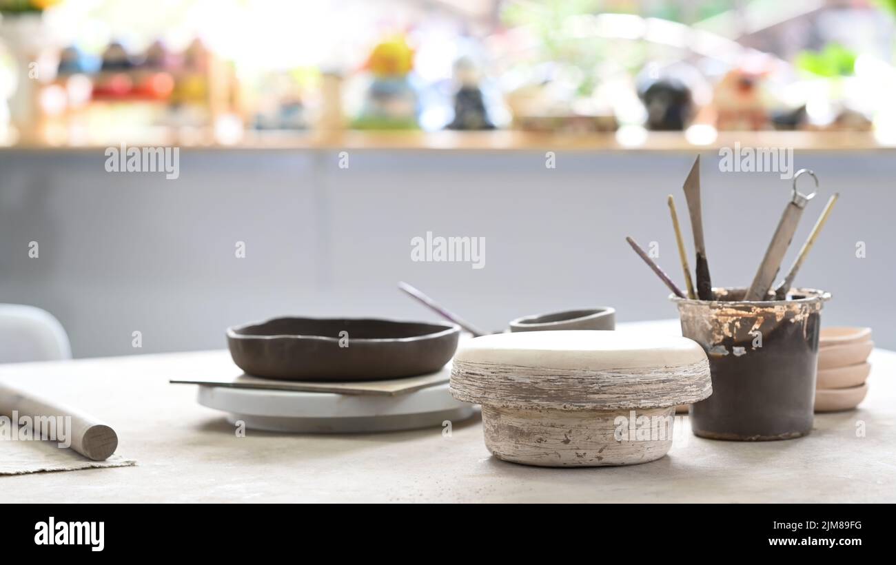 Handmade ceramic dish ware and pottery shaping tools on stone table in 