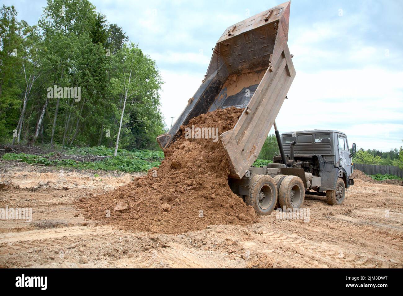 Dump-body truck unloads a ground Stock Photo