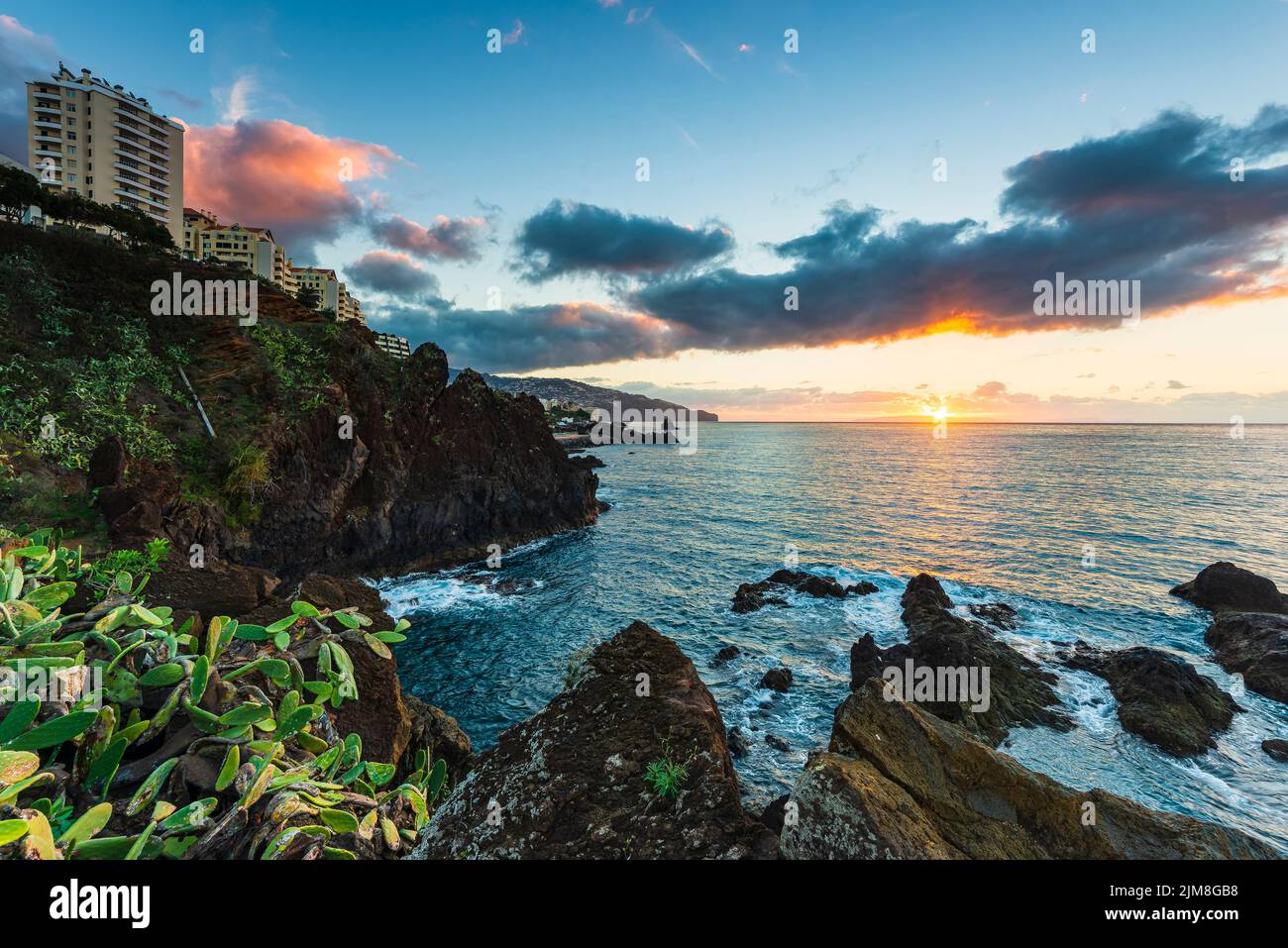 Sunrise at the sea besides buildings Stock Photo