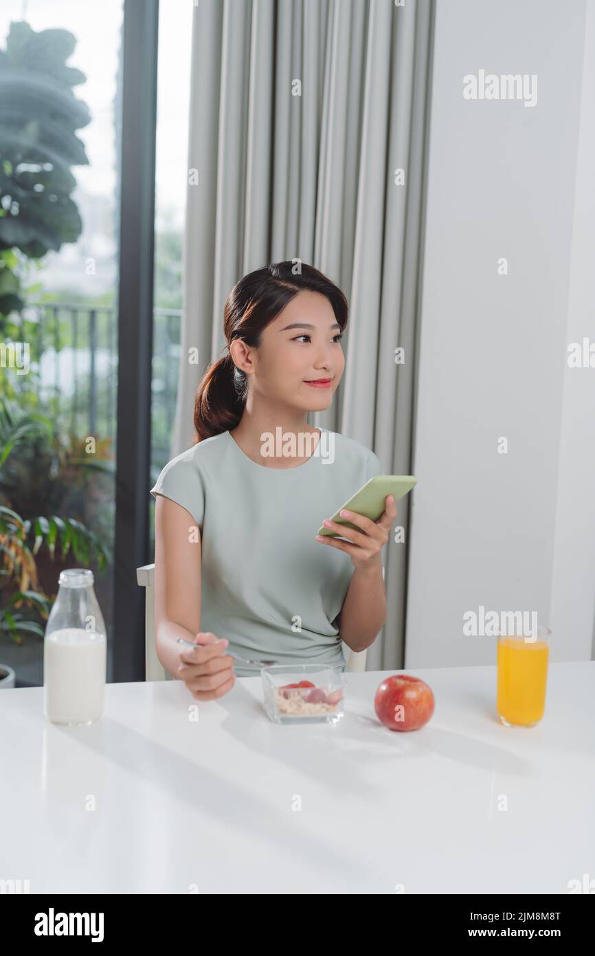 The girl uses the phone during breakfast Stock Photo