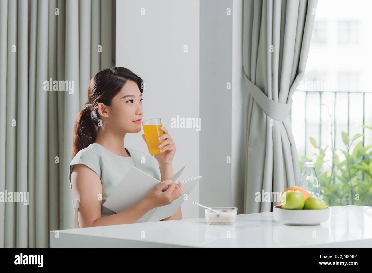 beautiful young woman reading book during breakfast at home Stock Photo