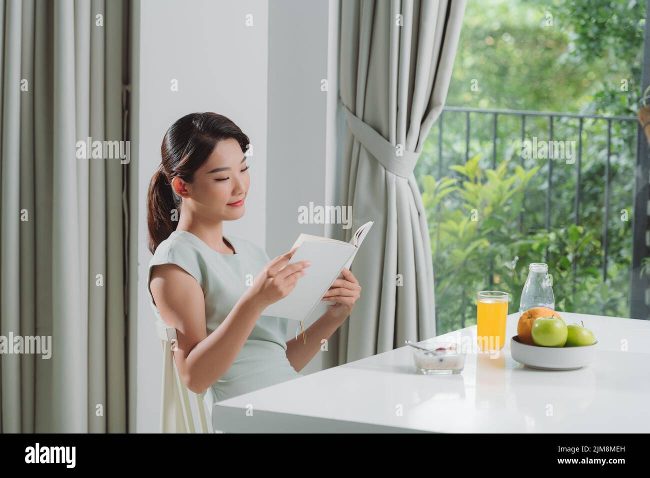 Woman is reading a book and having breakfast Stock Photo