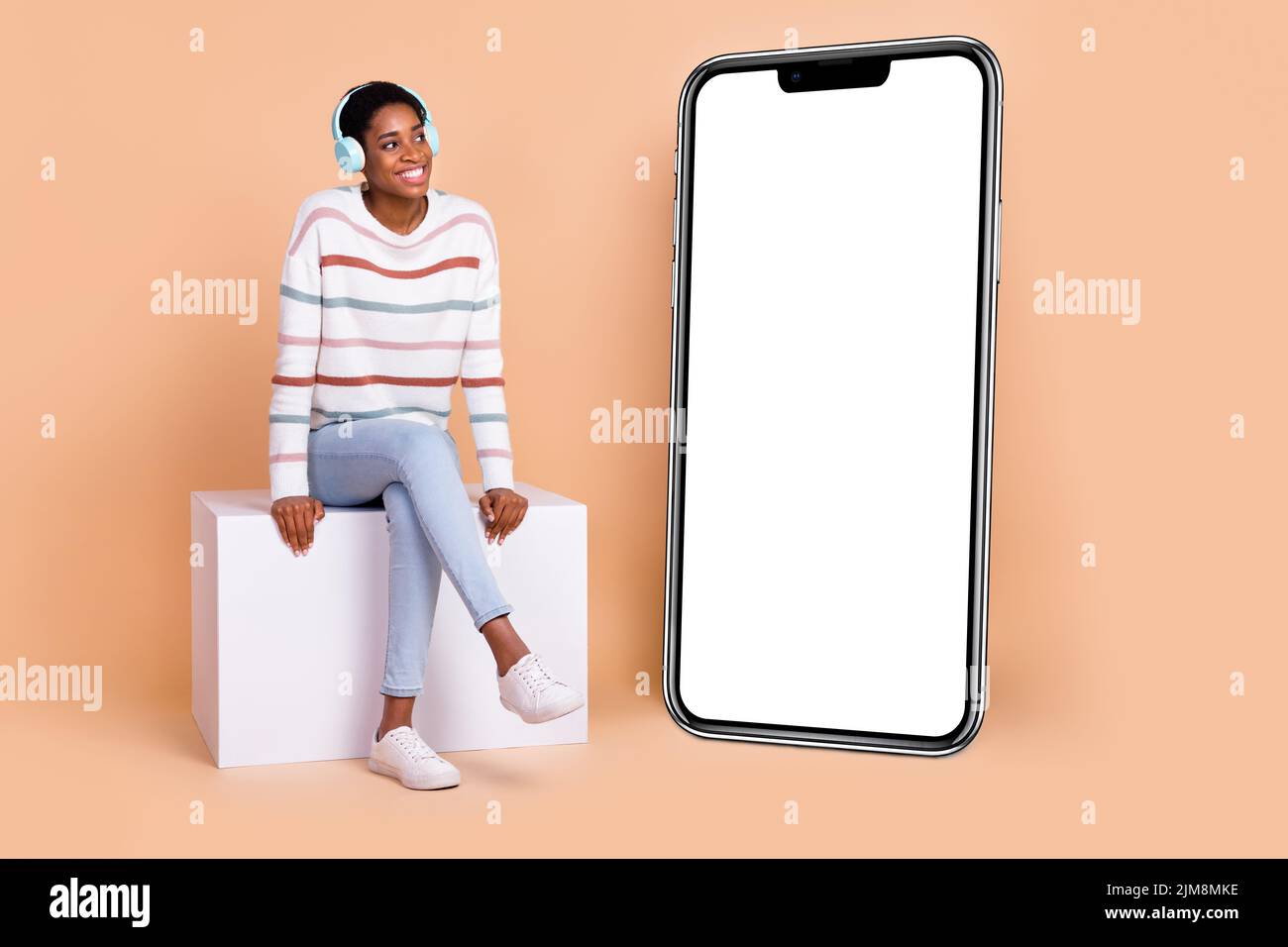 Photo of dreamy cute trans human dressed pullover sitting platform gadget empty space enjoy music isolated beige color background Stock Photo