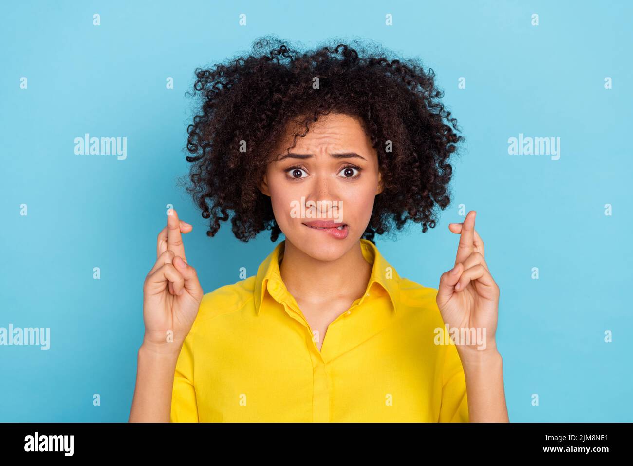 Portrait of attractive panicking lady crossed fingers biting lip wear smart casual isolated on blue color background Stock Photo