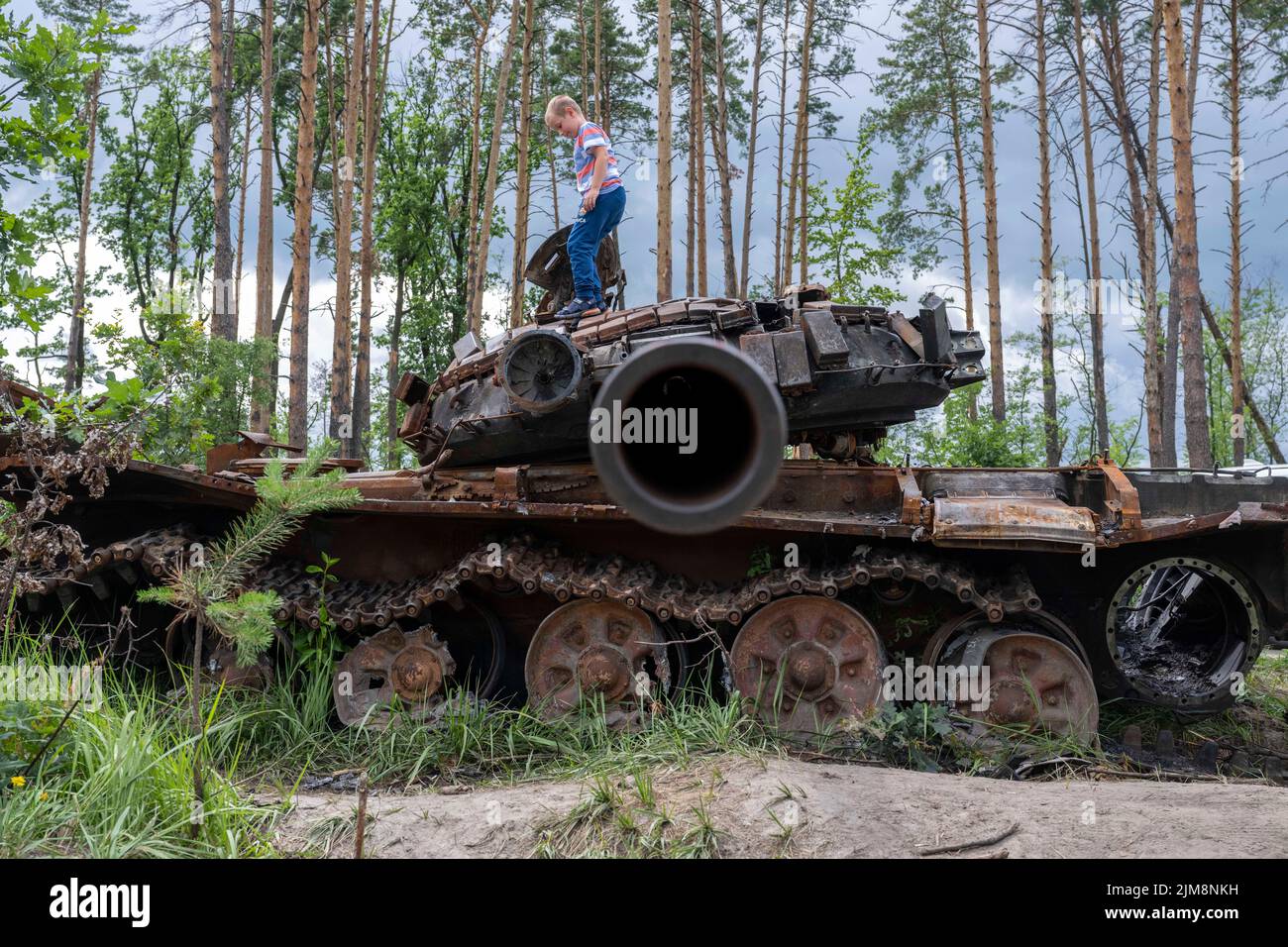 Bucha,Kyiv Oblast Picture shows a local child clambering on a destroyed Russian tank destroyed by Ukranian forces during the Russian invasion Stock Photo