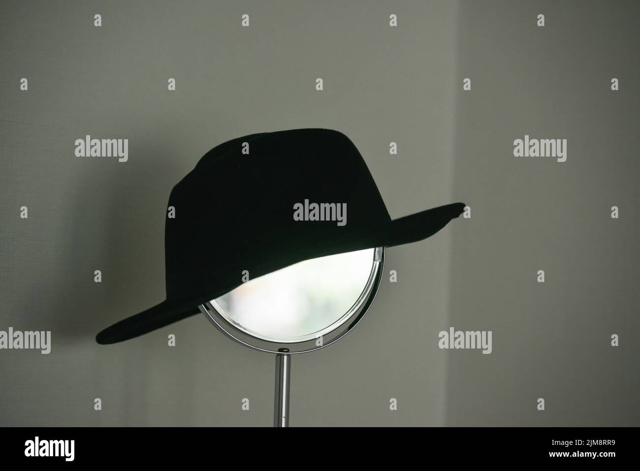 A black women's hat is placed on the make-up mirror. Interior accessory. Stock Photo