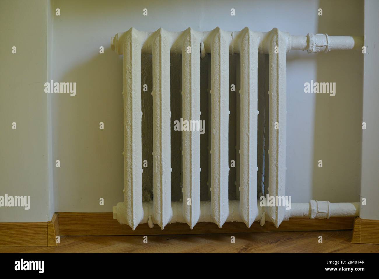 Pipes and a white heating radiator heat the room. heating season Stock Photo