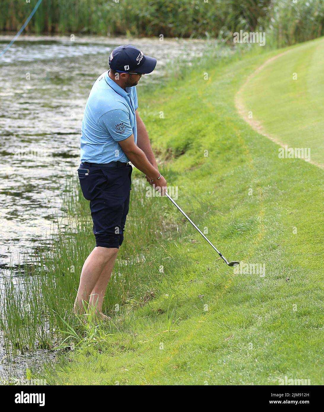England’s Matthew Southgate took his shoes and socks off to play a shot from the water on the third hole during day two of the Cazoo Wales Open at the Celtic Manor Resort in Newport, Wales. Picture date: Friday August 5, 2022. Stock Photo