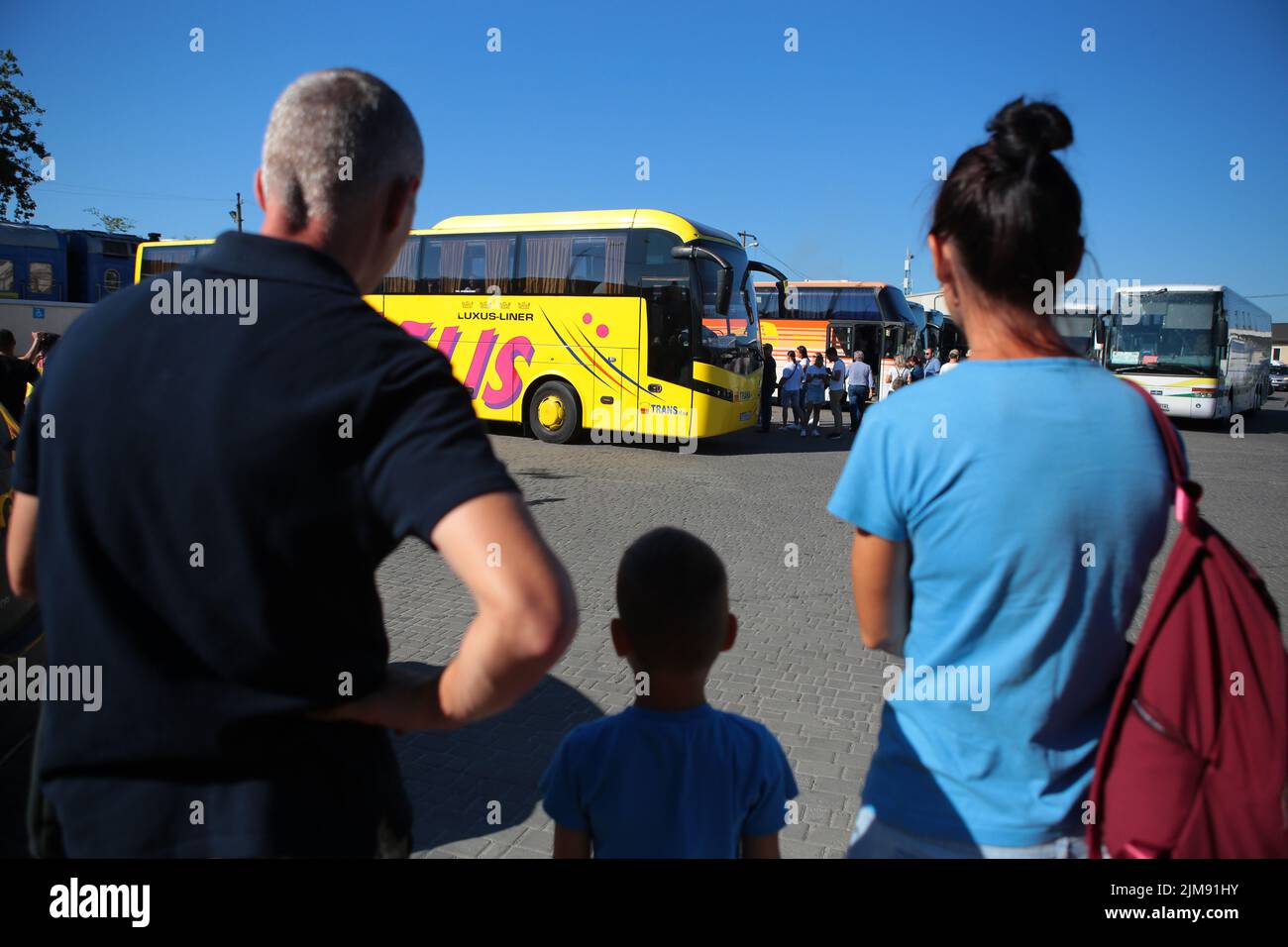 LVIV, UKRAINE - AUGUST 4, 2022 - A man, woman and child look at a bus at the Lviv railway station as one hundred children of internally displaced pers Stock Photo