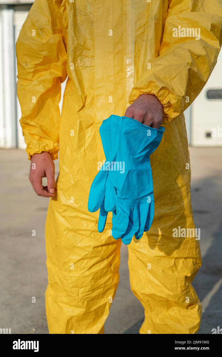 Front view of protective gloves and yellow overalls. Stock Photo