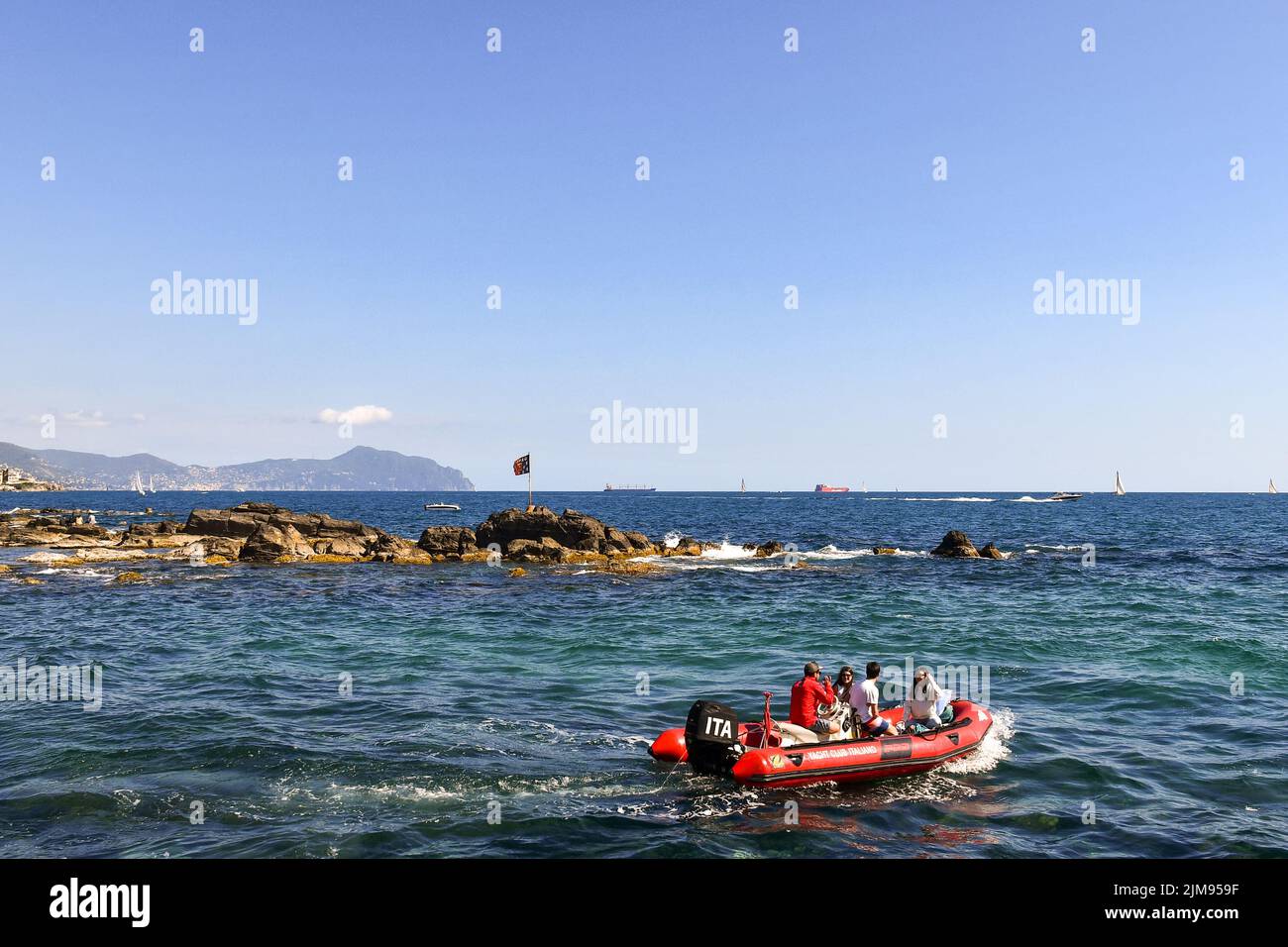 Two young couples sailing on a dinghy with the promontory of Portofino in the background, Boccadasse, Genoa, Liguria, Italy Stock Photo