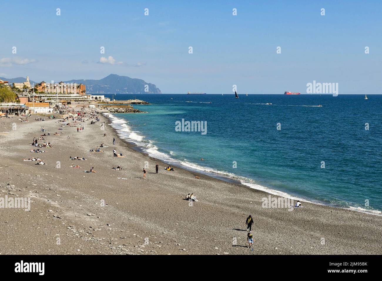 Scenic view of the beach of Albaro with tourists on Easter Monday and the promontory of Portofino on the sea horizon, Genoa, Liguria, Italy Stock Photo