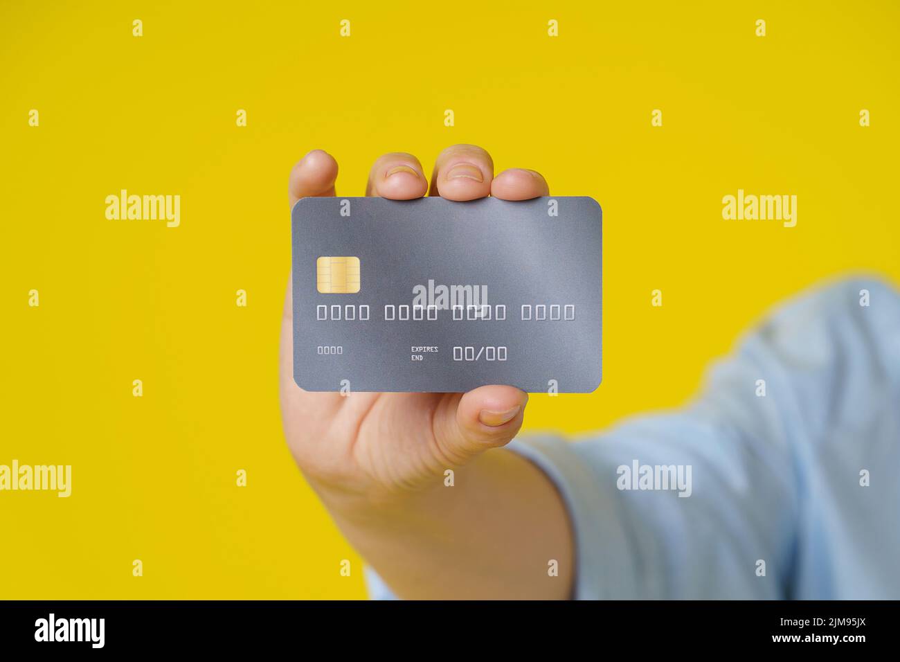 Credit, debit cad close up in hand of mature woman showing it on camera, customer online payment or shopping online, isolated on yellow background. E-commerce, online banking concept. Stock Photo