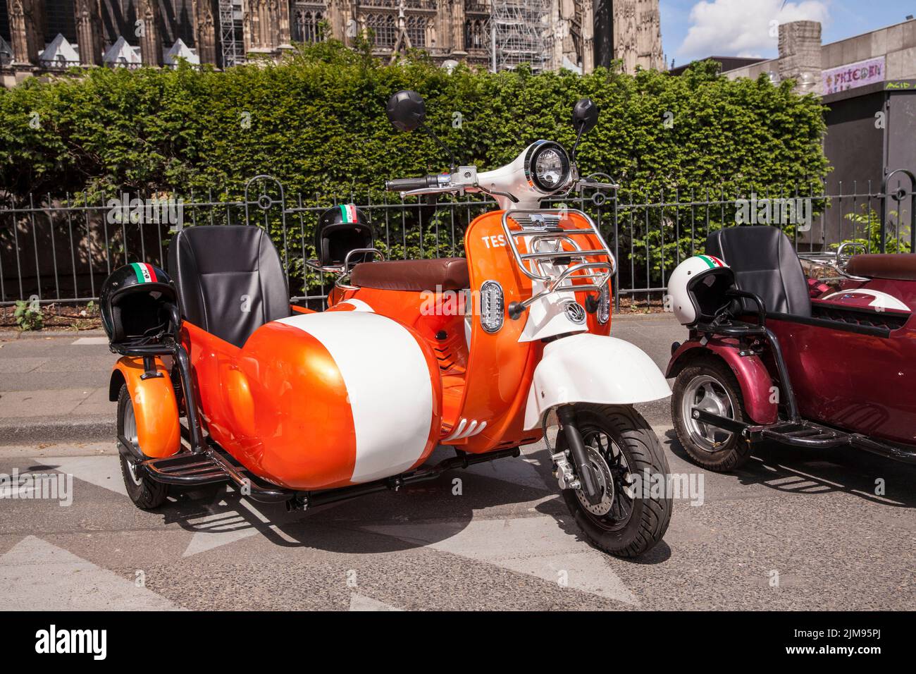 E-Vespina scooters with sidecars are available for rent for city tours near the cathedral, Cologne, Germany. E-Vespina Roller mit Seitenwagen stehen z Stock Photo