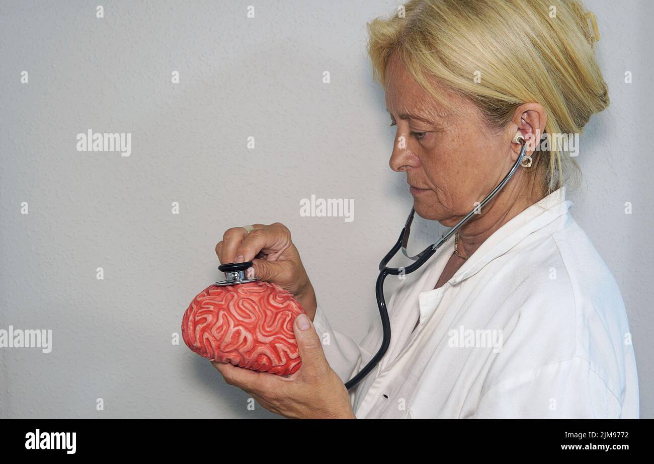 A female doctor puts the stethoscope on a rubber brain Stock Photo - Alamy