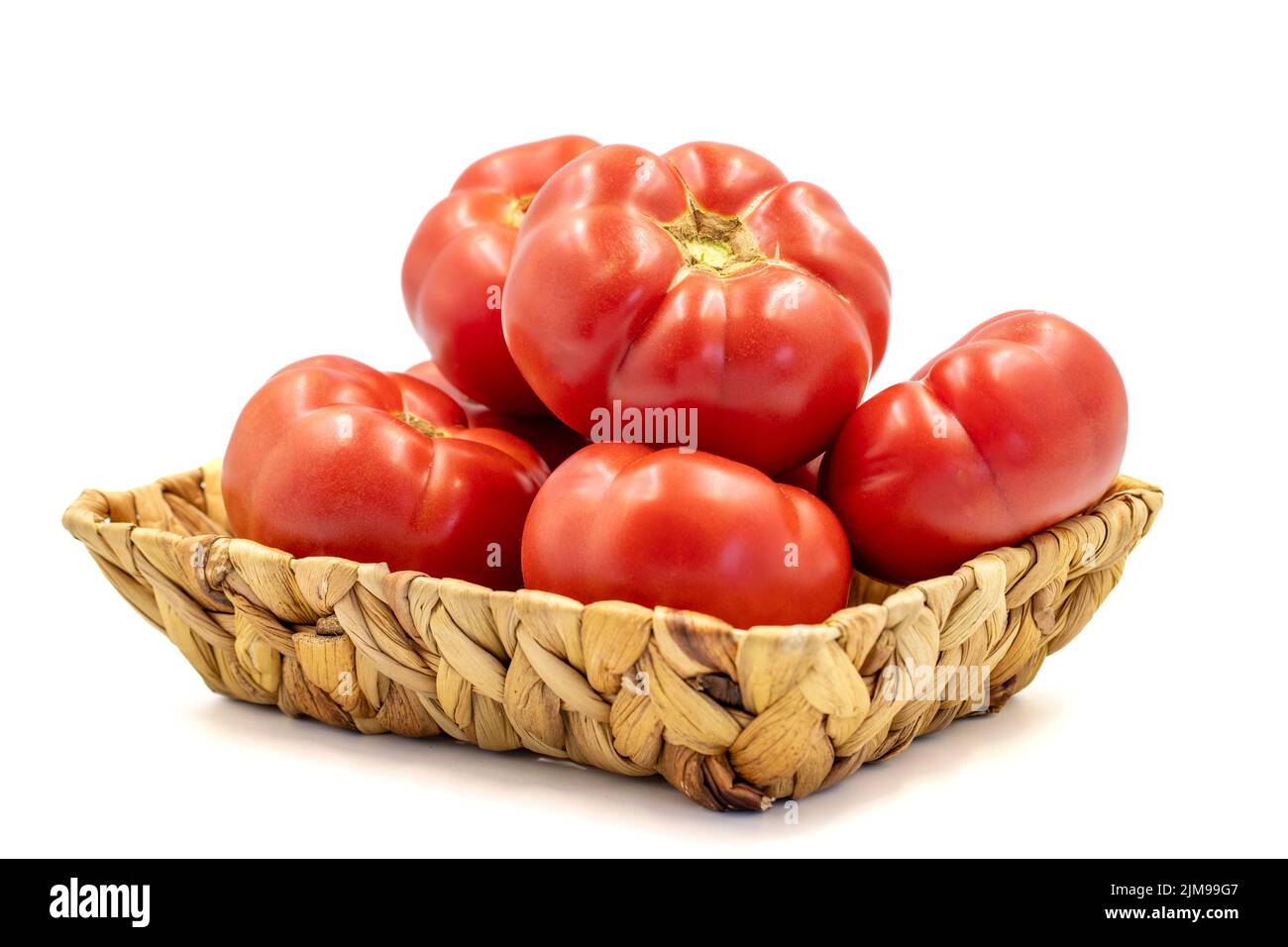 Ripe Tomatoes. Fresh and raw red tomatoes in basket isolated on white background. Organic food. close up Stock Photo