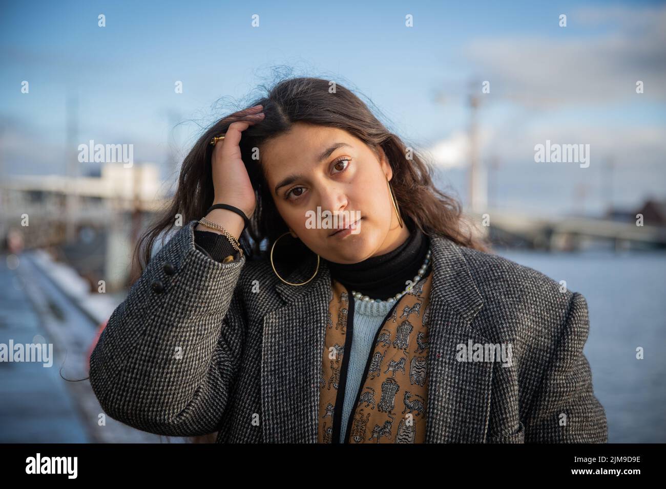 Portrait of a young Moroccan girl outside in winter with thoughtful and worried expression, she touches her hair with her hand Stock Photo