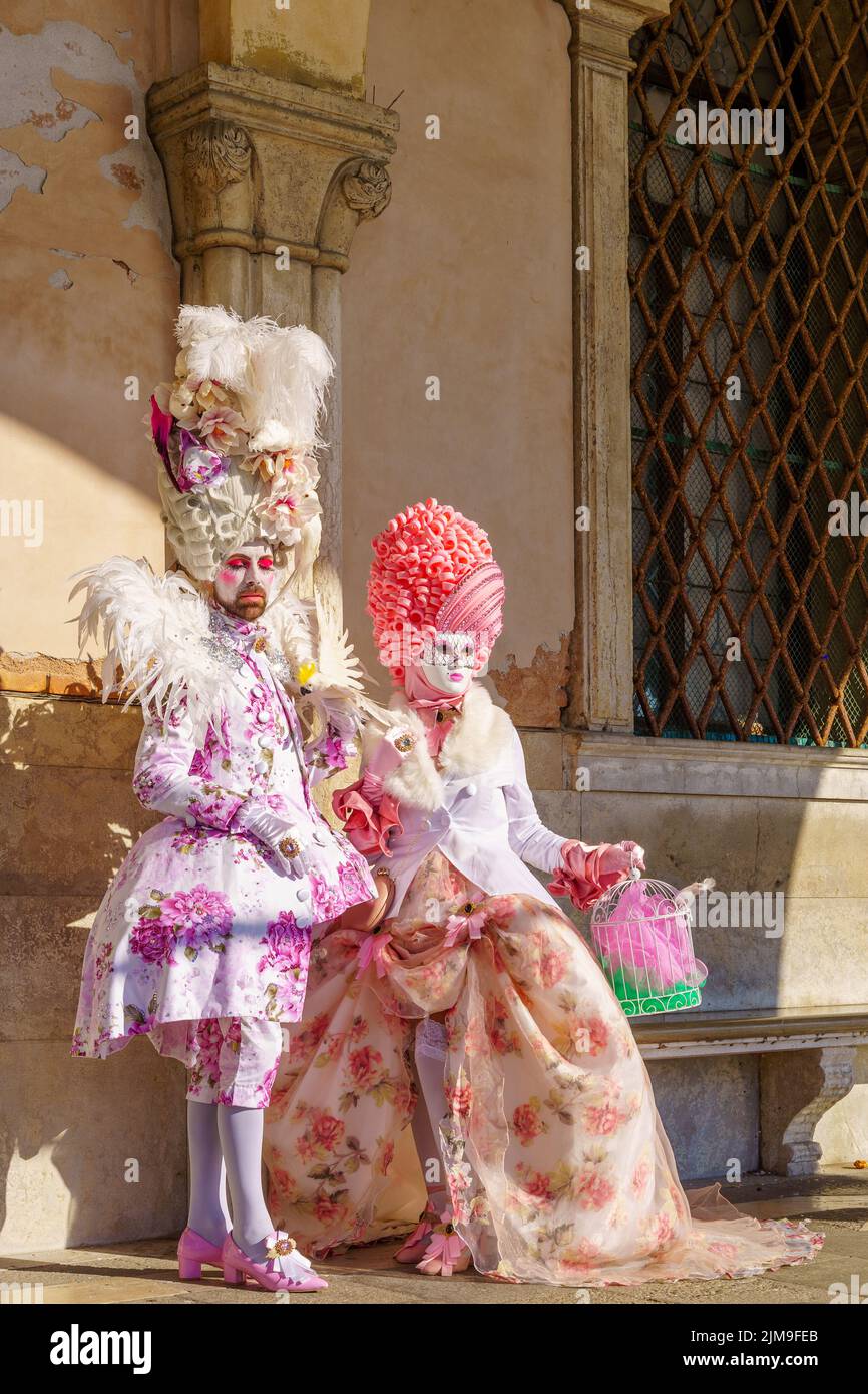 Venice, Italy - February 28, 2022: Couple dressed in traditional costumes, in Riva degli Schiavoni waterfront, part of the Venice Mask Carnival, Venet Stock Photo