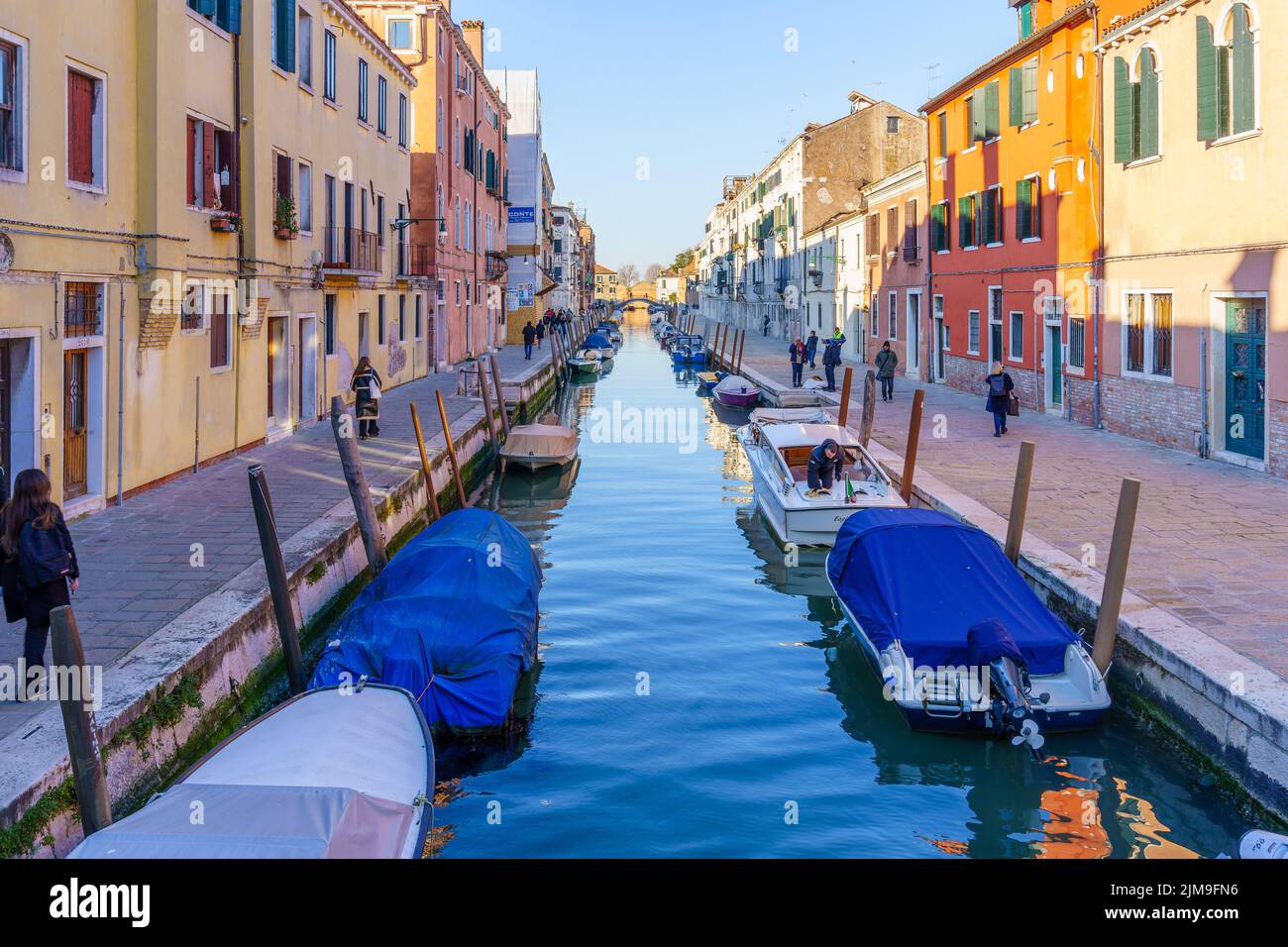Venice, Italy - March 01, 2022: View of Canal, with colorful buildings, bridges, boats, locals, and visitors, in Venice, Veneto, Northern Italy Stock Photo