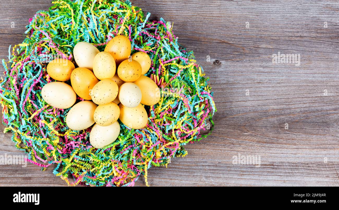 Easter eggs on top of colorful Mache paper with rustic wooden boards Stock Photo