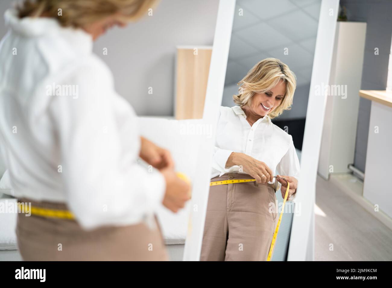Smiling Slim Woman Looking At Her Reflection In Mirror Stock Photo
