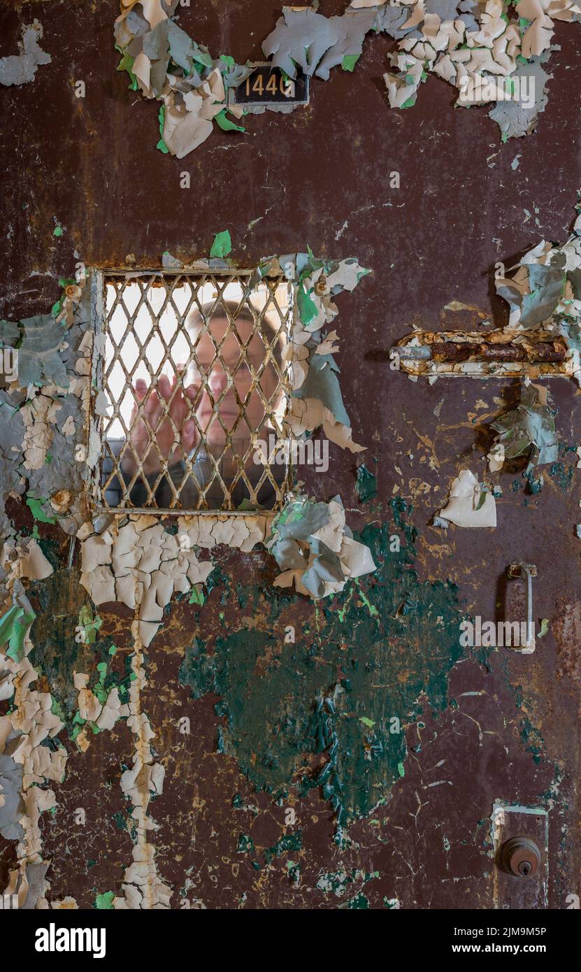 Senior man behind locked barred door in cell Stock Photo