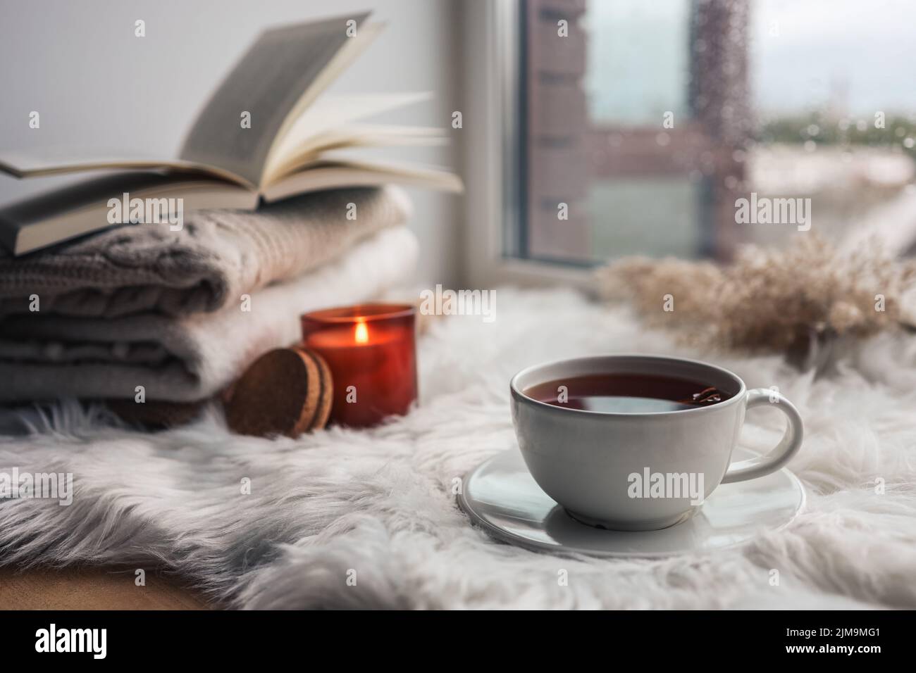 Beautiful autumn composition with burning candle and cup of tea on window sill Stock Photo