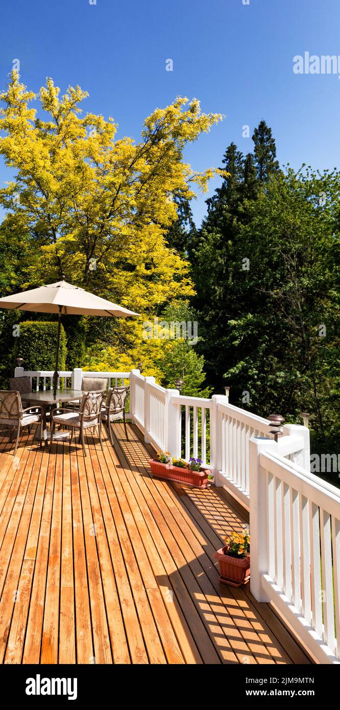 Outdoor cedar deck with blooming trees and blue sky in background Stock Photo