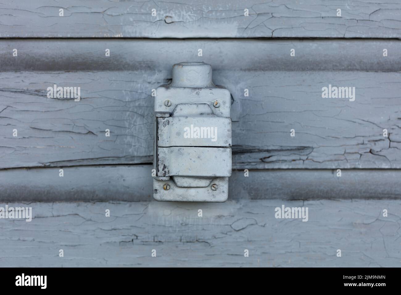 Old electrical outlet box with lead paint peeling off of wood sliding Stock Photo