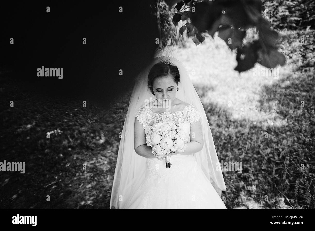 Portrait of cute bride with peony wedding bouquet at hands at wood, b&w ...