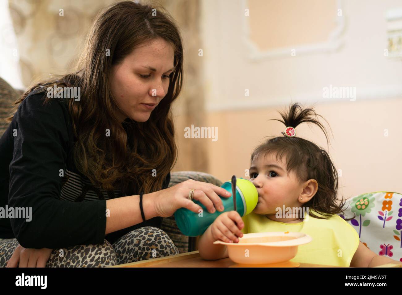 A close upbeautiful woman with her daughter giving her lunch and drinking water, light colors Stock Photo
