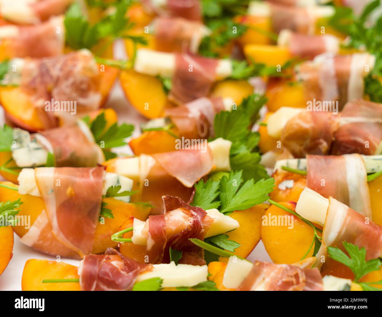 Many small peach and gorgonzola wrapped prosciutto snacks Stock Photo