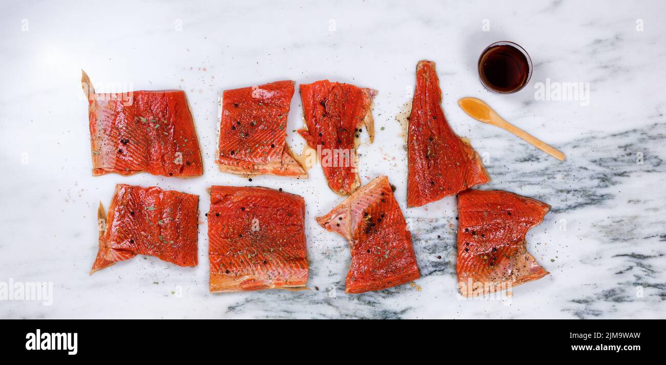 Raw salmon fillets prepared for smoke cooking on marble stone countertop Stock Photo