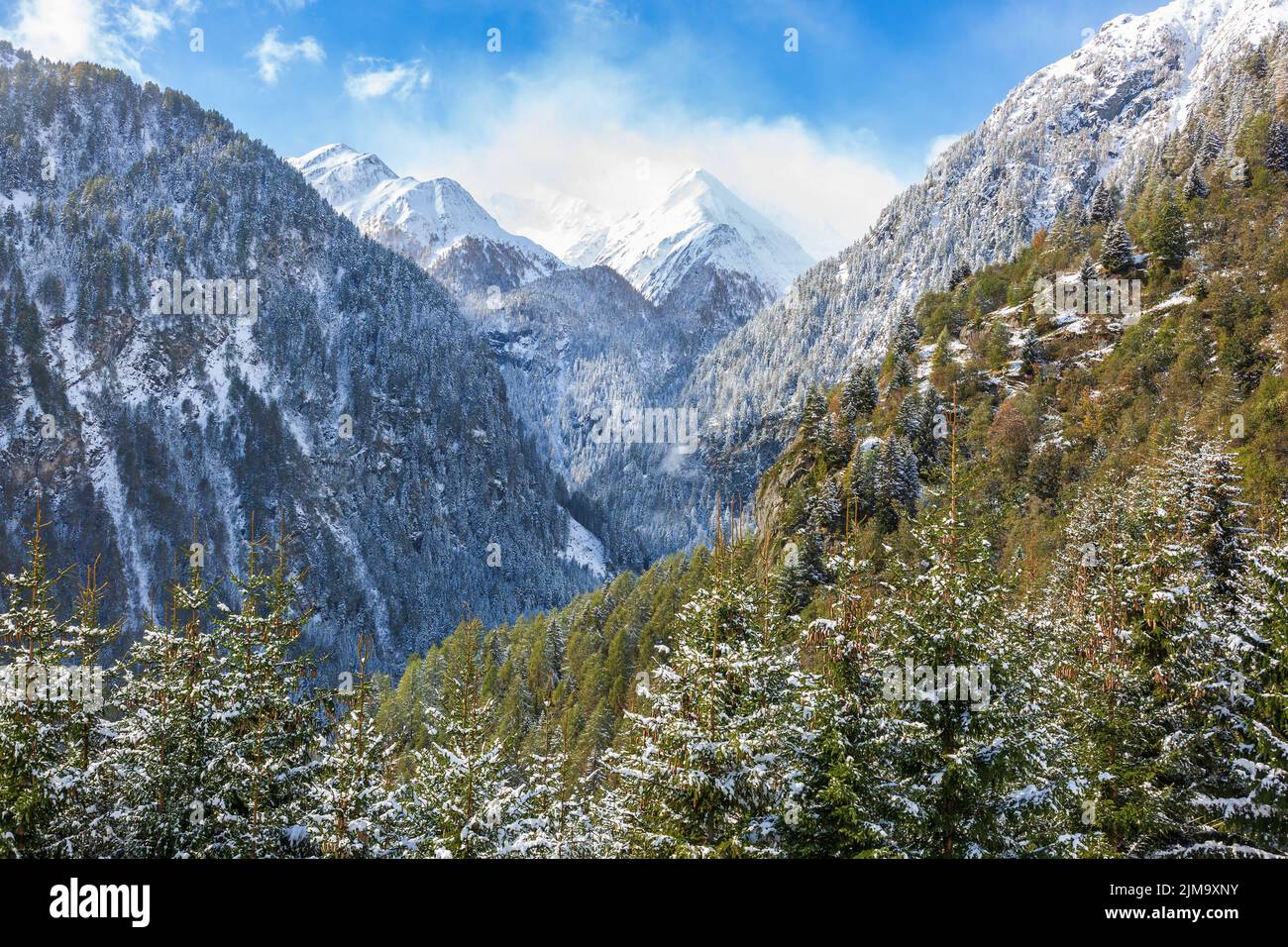 View at mountain ravine with snow capped mountain peaks Stock Photo - Alamy