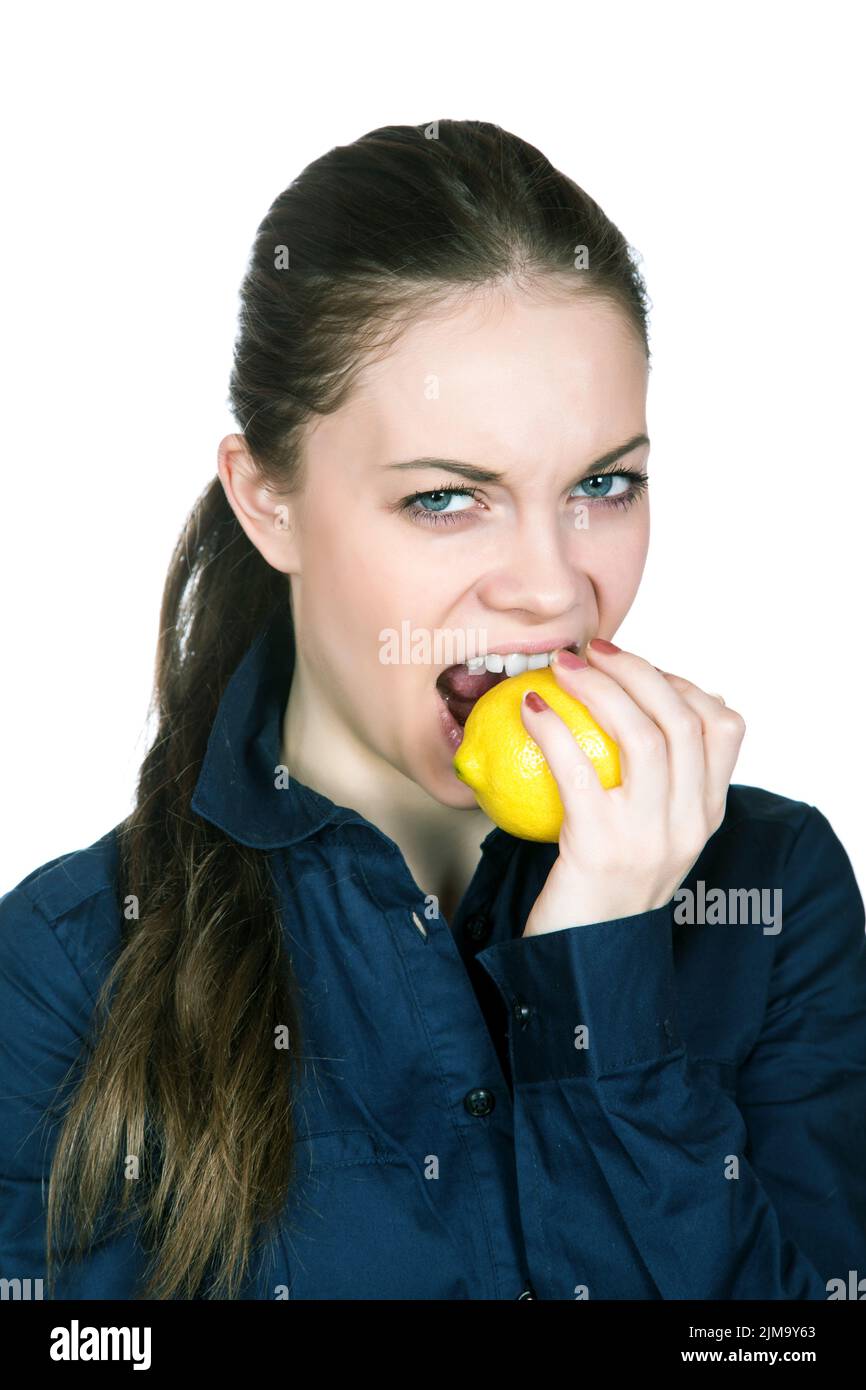 The girl with a sour mine on the person bites  lemon Stock Photo