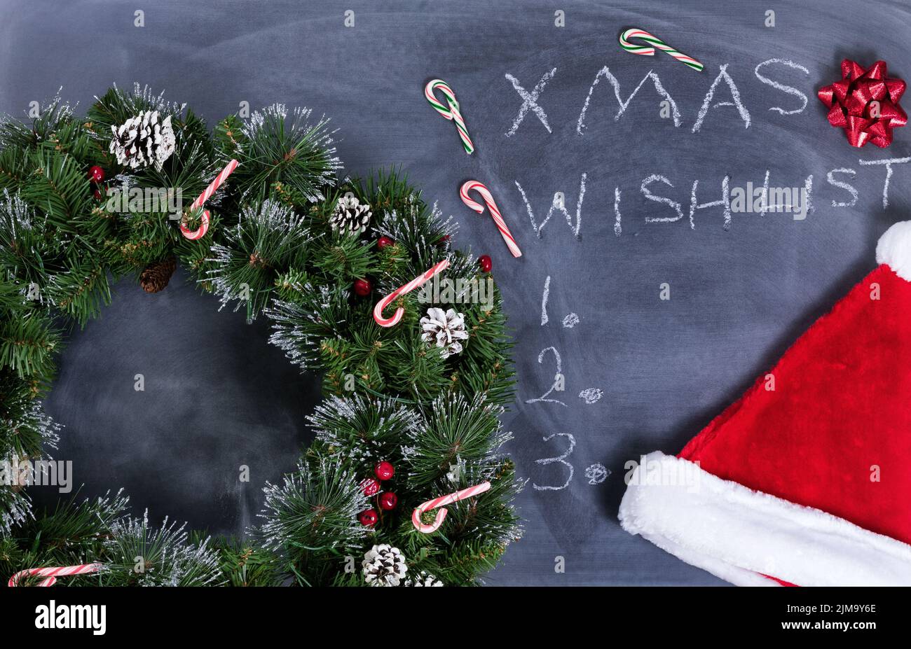 Erased black chalkboard with wreath and other Xmas items plus text writing Stock Photo