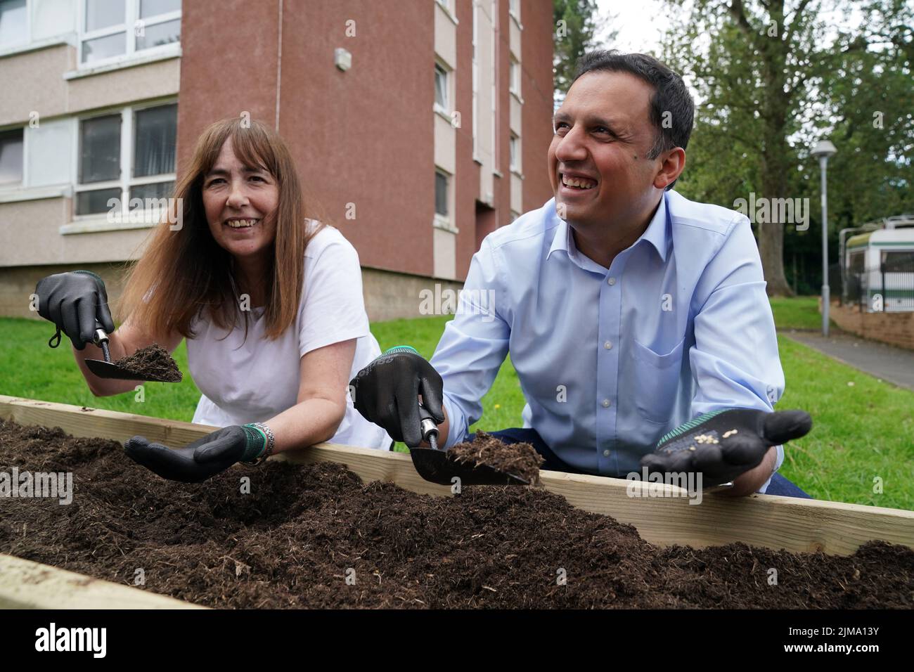 Scottish Labour leader Anas Sarwar helps Sharon Bowers plant seeds in a community garden during his to visit Acre Community Hall, Glasgow, where he met volunteers in the food bank and later planted seeds in a vegetable patch. Picture date: Friday August 5, 2022. Stock Photo