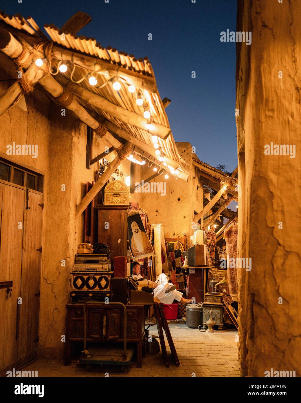 A vertical shot of a young boy sitting at an outdoor market with the